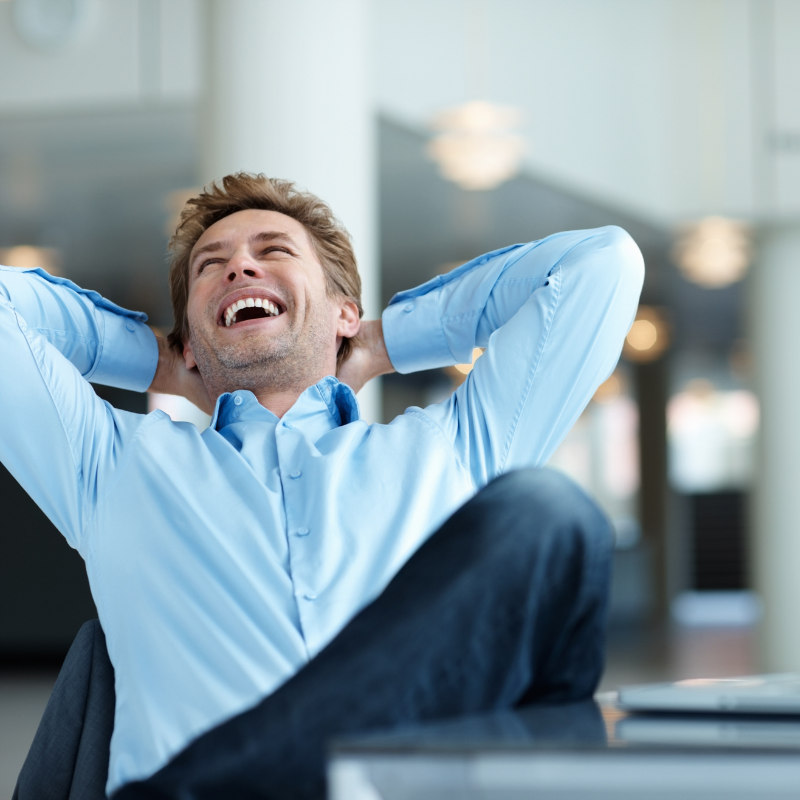 Man leaning back in his chair, laughing joyfully, representing the freedom that comes from not taking oneself too seriously.
